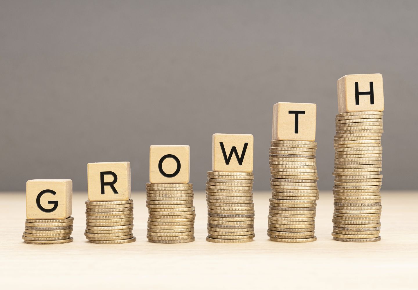 piles of coins increasing in size from left to right, with the letters G-R-O-W-T-H on top of each