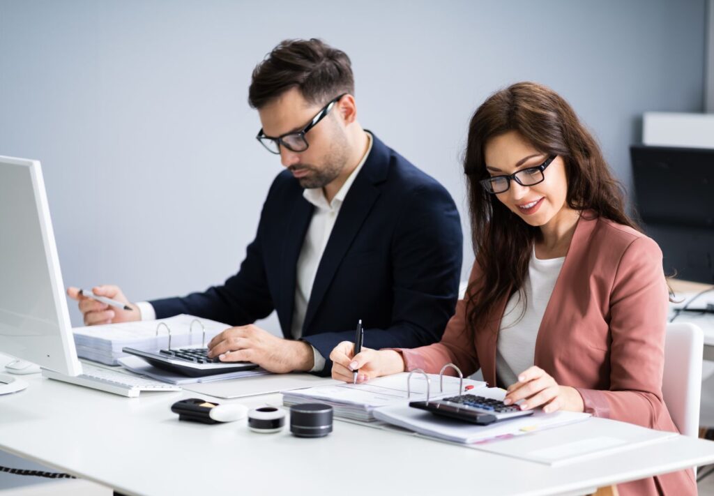 man and woman working at desk with calculators