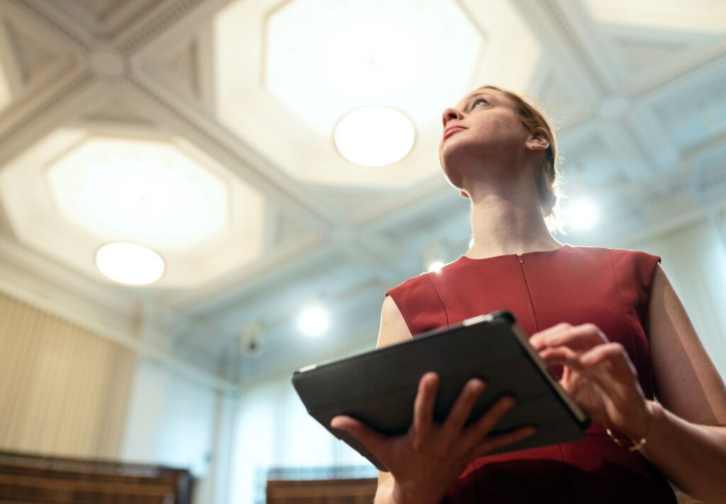 woman holding a tablet looking up at ceiling lights