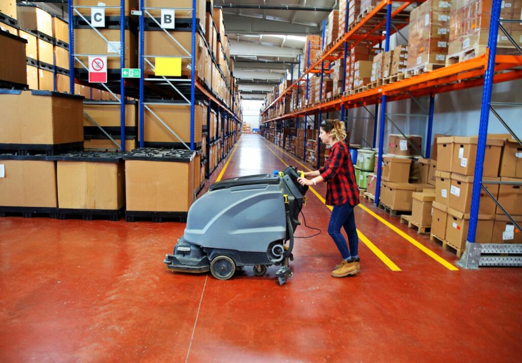 A woman using a vacuum cleaner to clean a warehouse