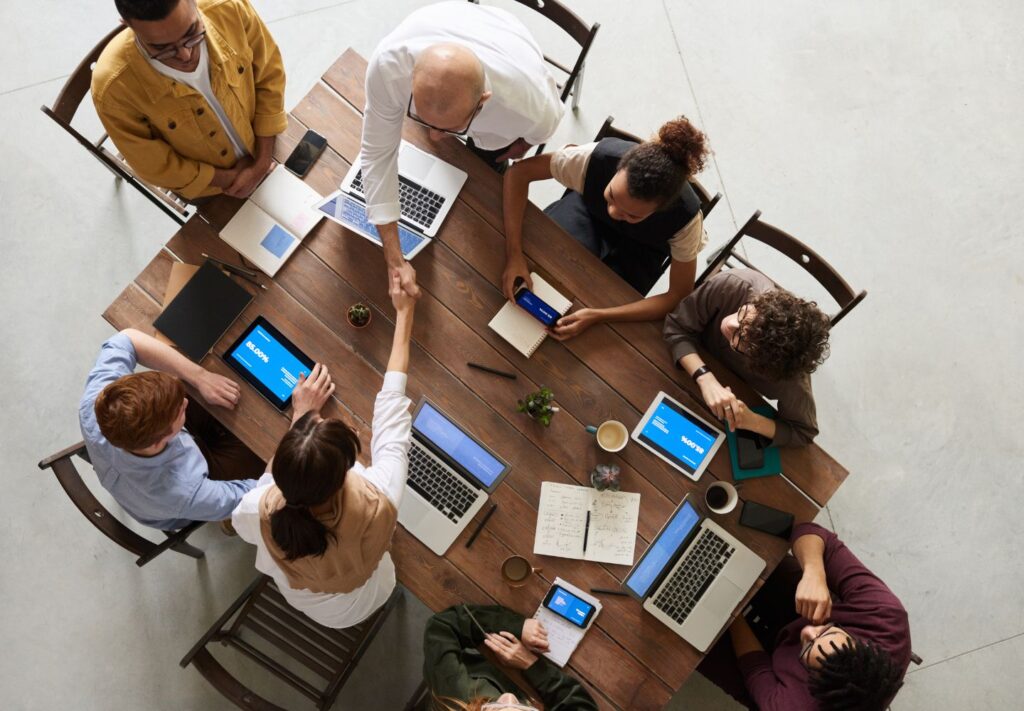 a group of people around a table with laptops