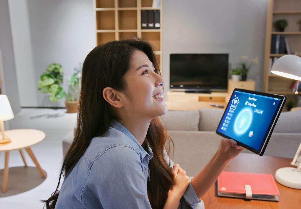 a woman holding a tablet with lighting controls on it